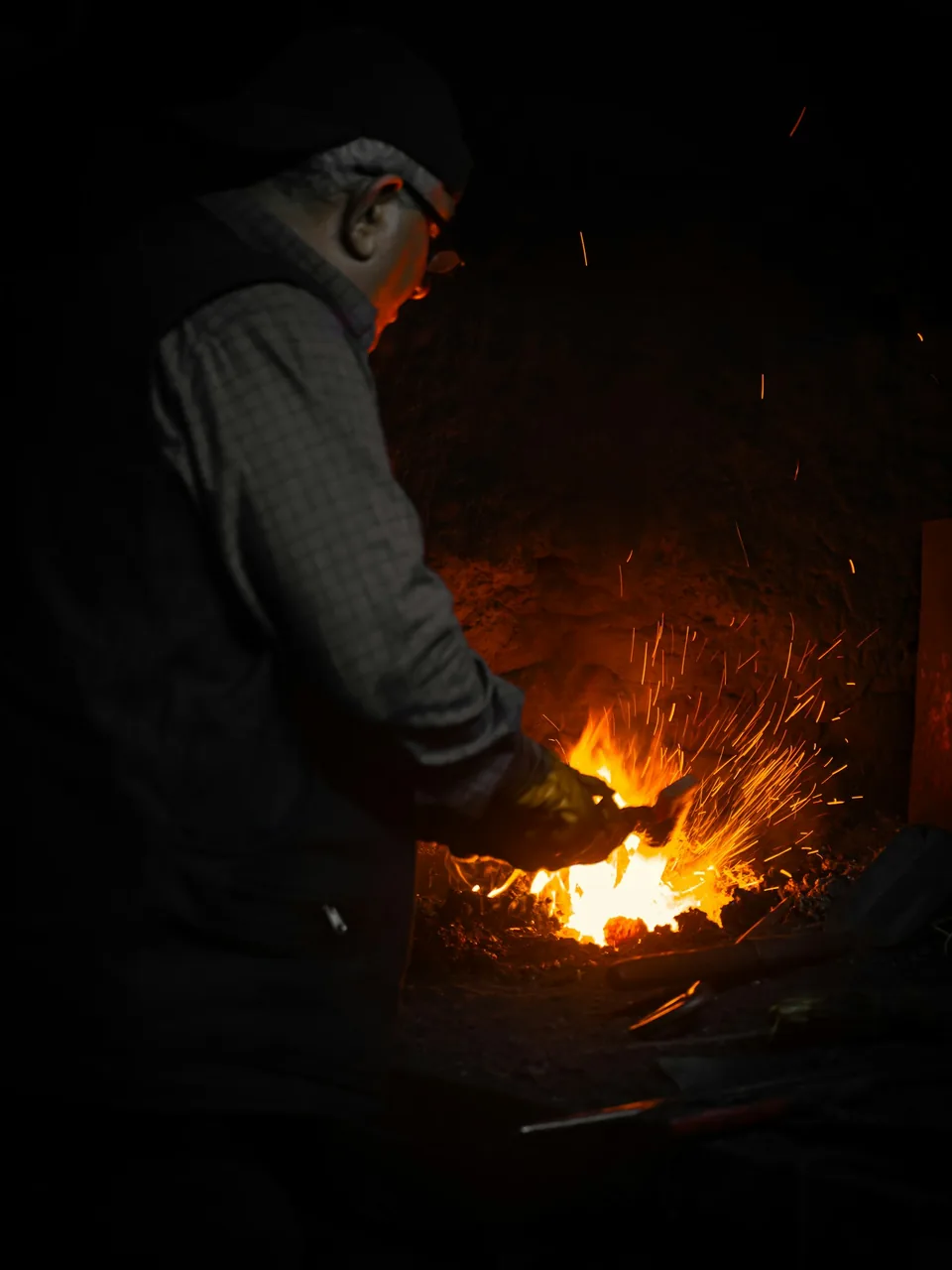 Fragua encendida en un taller de cuchillería con chispas saltando sobre el yunque